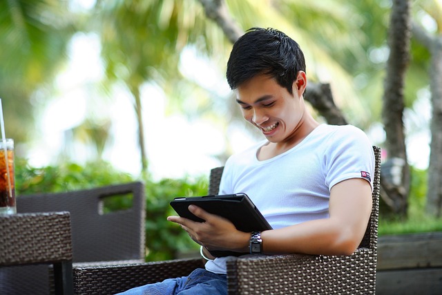 Ein Onlinekursteilnehmer sitzt im Grünen am Tablet